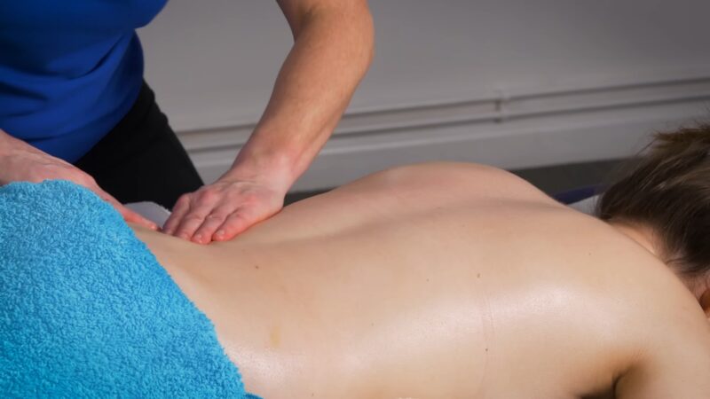 The physiotherapist is massaging the patient's back
