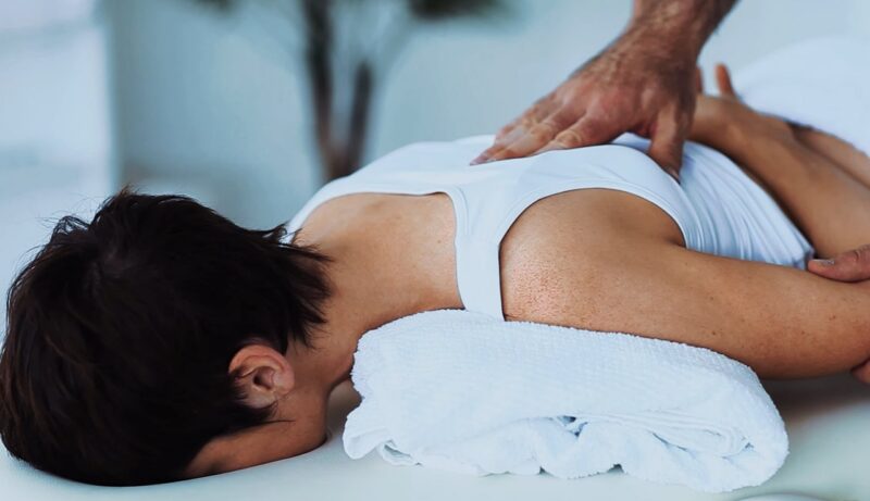The physiotherapist massages the spine of the patient lying down